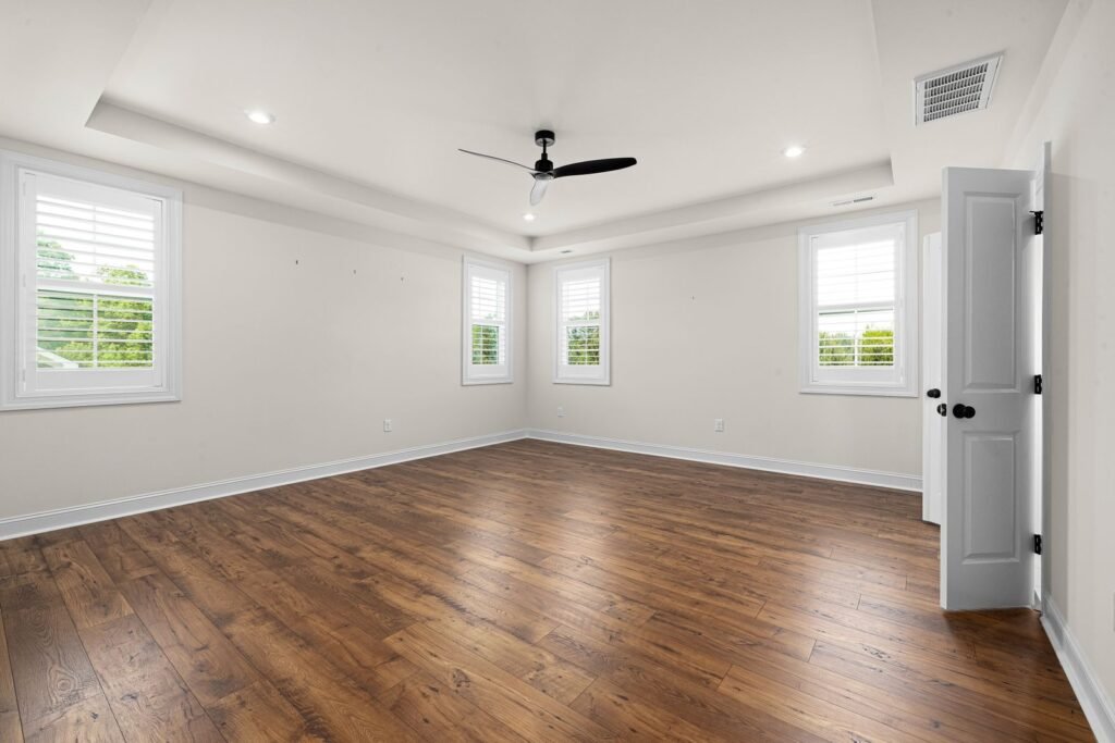 Bright empty room with white walls, windows and hardwood floor