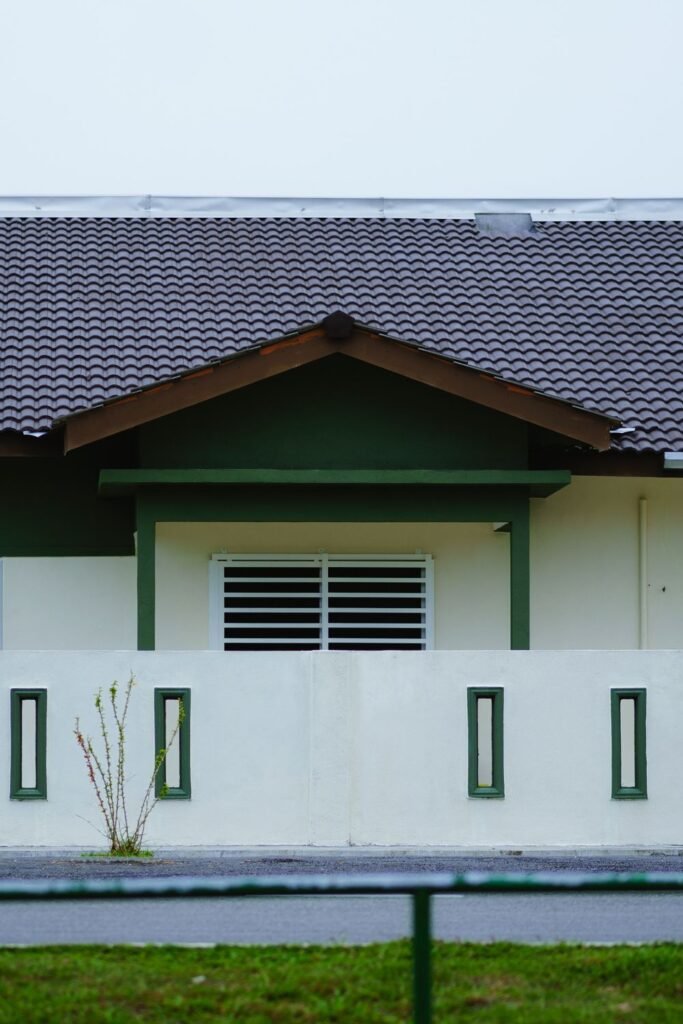 Exterior of a house with white painted walls, green trim and a tile roof